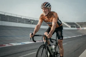 Cycliste professionnel vétéran appuyé sur son vélo de course dans un vélodrome, illustrant le retour controversé de Lance Armstrong dans le cyclisme en 2026
